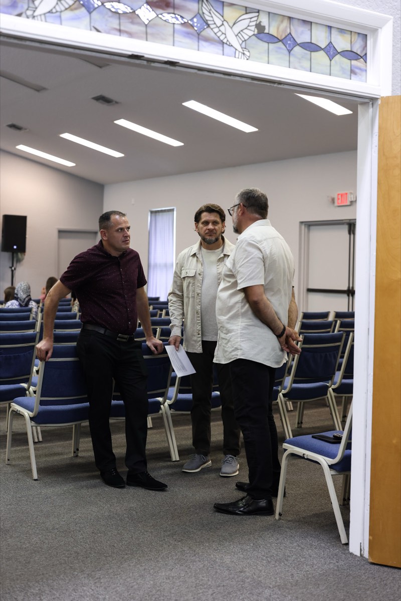 Three church members talking together, one holding printed notes